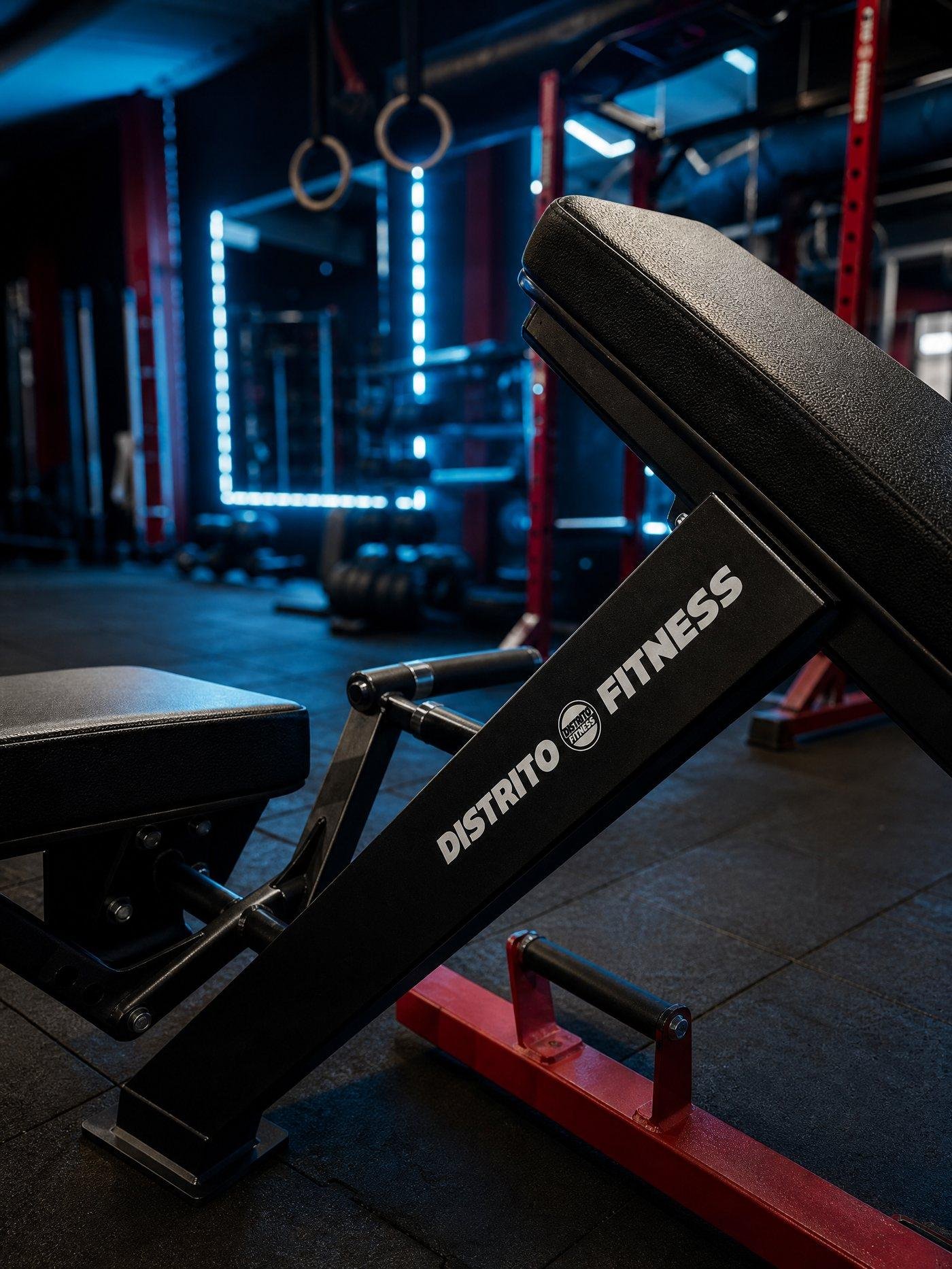 Banco de pesas con la marca Distrito Fitness, con el rack e iluminación LED azul de fondo
